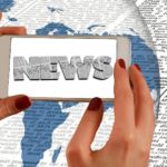 ידיים עם סמארטפון שעליו עיתון דיגיטלי