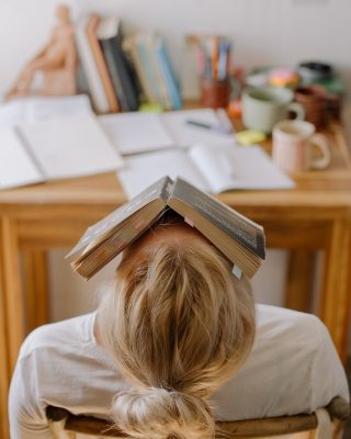 ילדה בבית ספר עם ספר מונח על הפנים